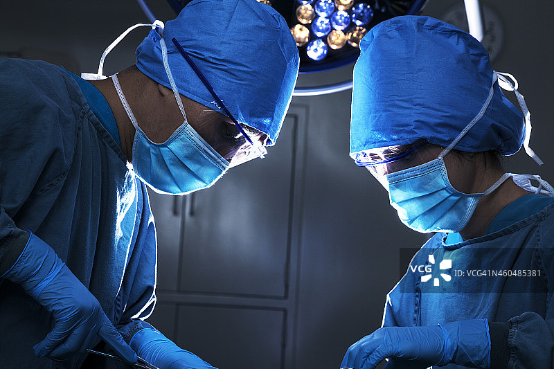 两个外科医生低头，集中注意力在手术台上图片素材