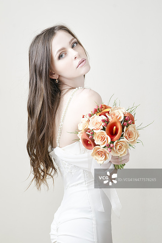 年轻美丽的新娘拿着婚礼上的橙色花束图片素材