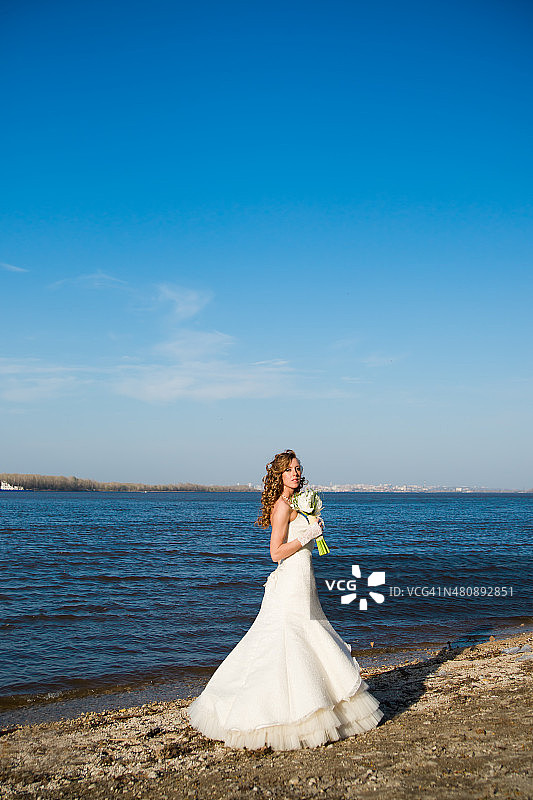 美丽的新娘穿着白色的裙子在河边图片素材