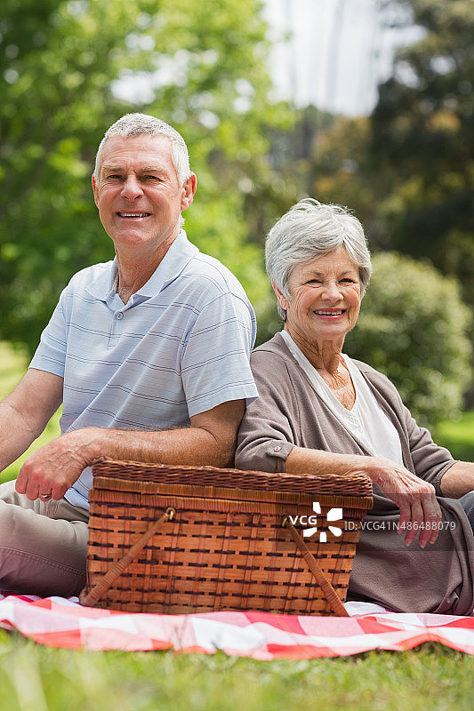 带着野餐篮微笑的老年夫妇在公园里图片素材