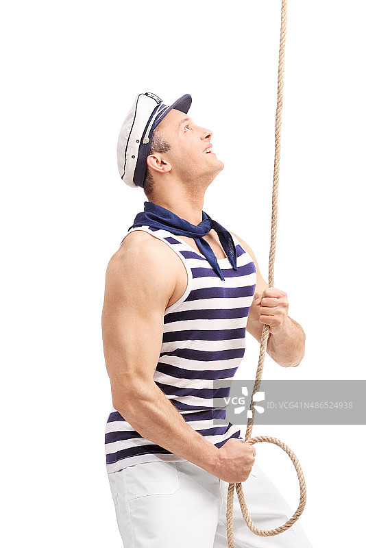 年轻的男水手拉着一根绳子，向上看图片素材
