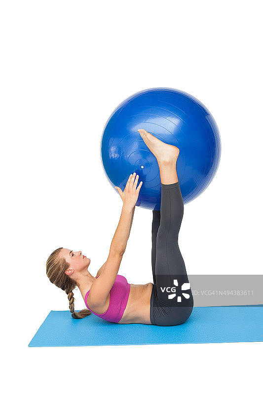 一个健康的女人用健身球运动的侧视图图片素材