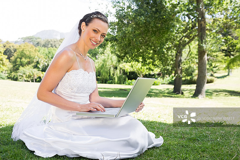美丽的新娘在花园里使用笔记本电脑图片素材