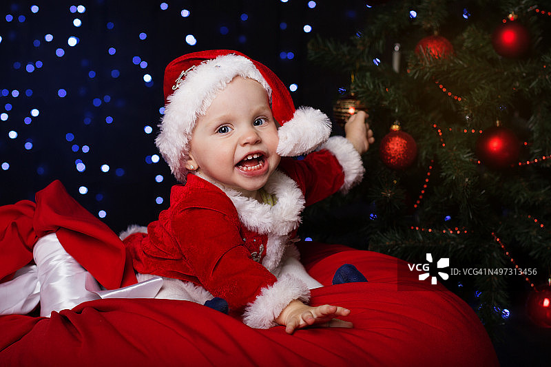 快乐的婴儿坐在圣诞树旁图片素材