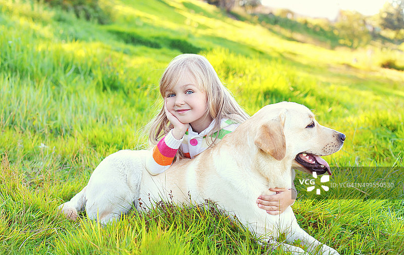 快乐的孩子和拉布拉多猎犬躺在草地上图片素材