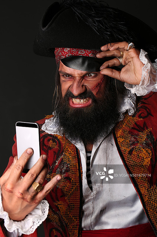 一个穿着海盗服装拿着手机的男人的肖像图片素材