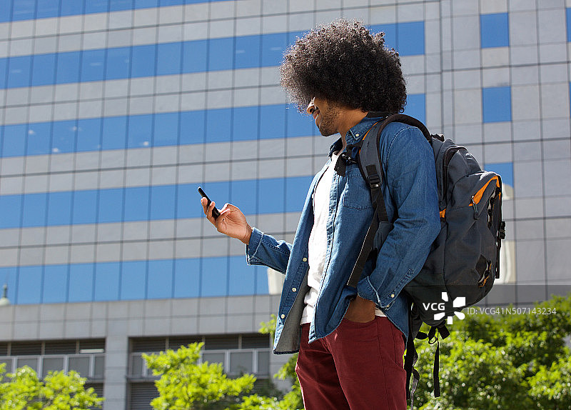一个年轻人拿着手机走在城市里图片素材