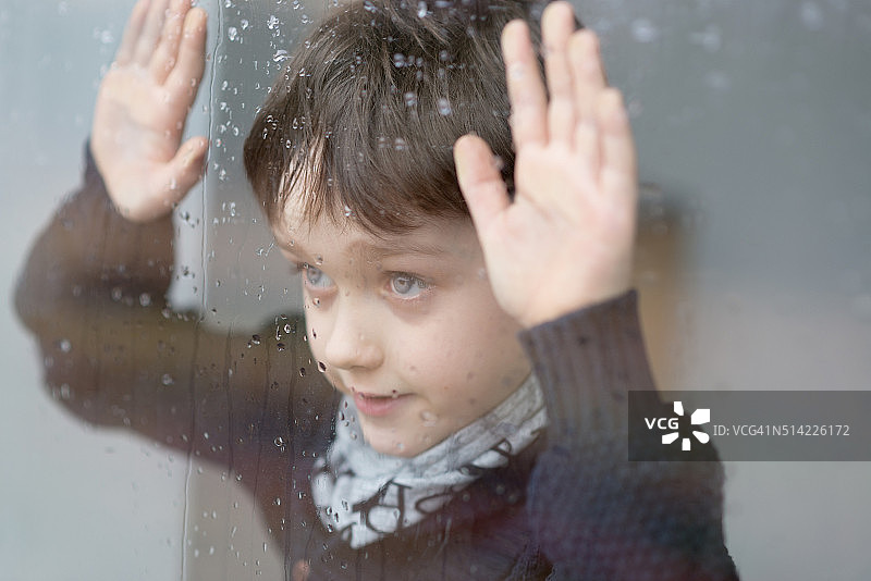 一个7岁的小男孩站在窗边图片素材