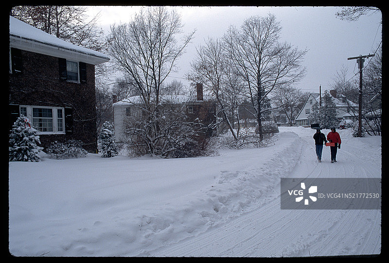 一对夫妇走在下雪的住宅路上图片素材