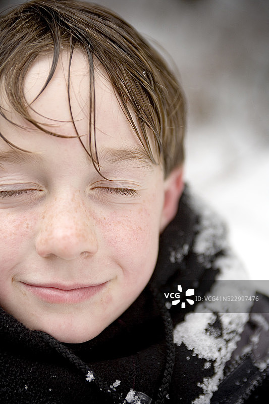 微笑的男孩站在雪中图片素材