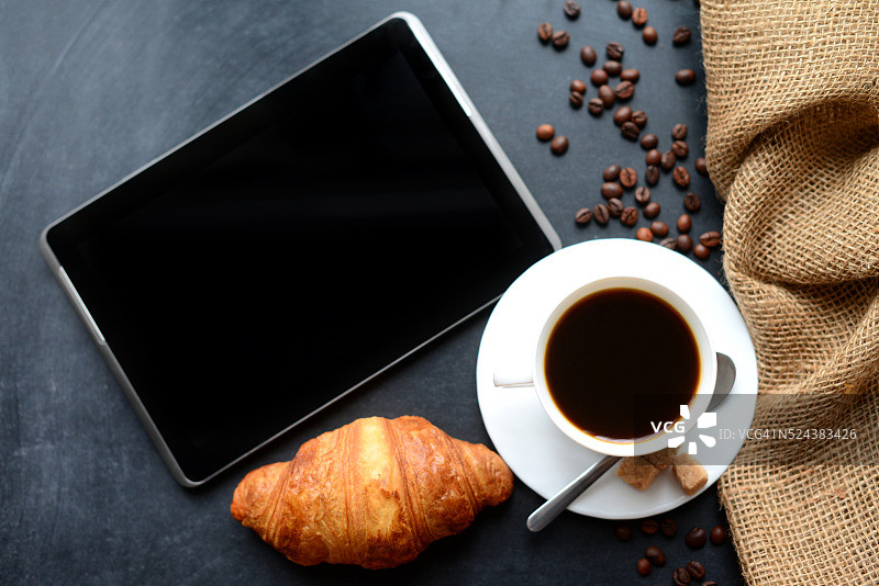 一杯咖啡和黑色背景的数码平板电脑图片素材