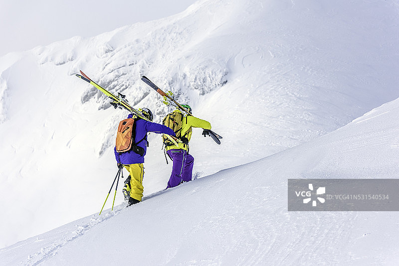 两个滑雪者爬上一座雪山图片素材