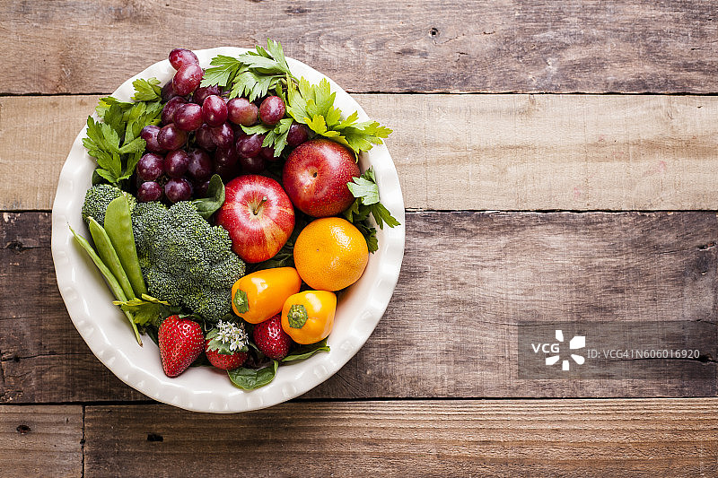 质朴的木桌上摆放着五颜六色的有机水果、蔬菜。图片素材