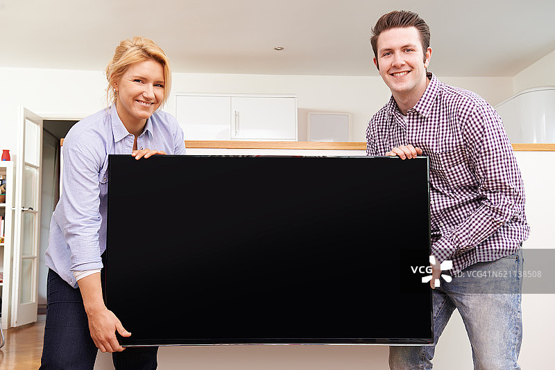 兴奋的夫妇在家里安装新电视机图片素材