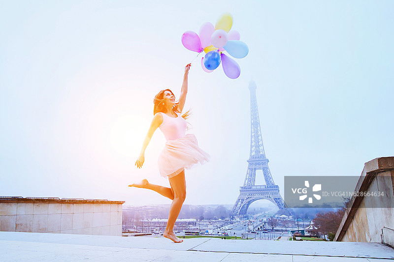 拿着气球的女孩在巴黎埃菲尔铁塔附近跳图片素材