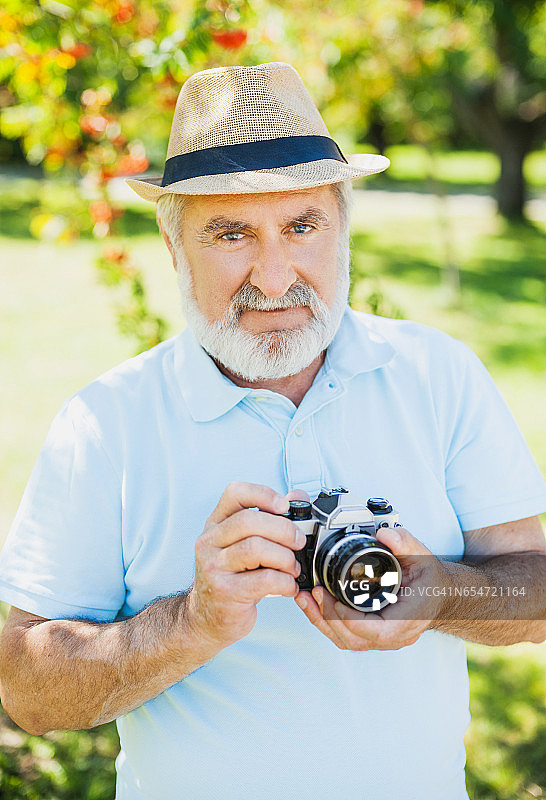 一位老人正在用相机拍照图片素材