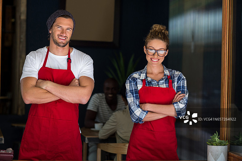 微笑的服务员和服务员站在外面双臂交叉café图片素材
