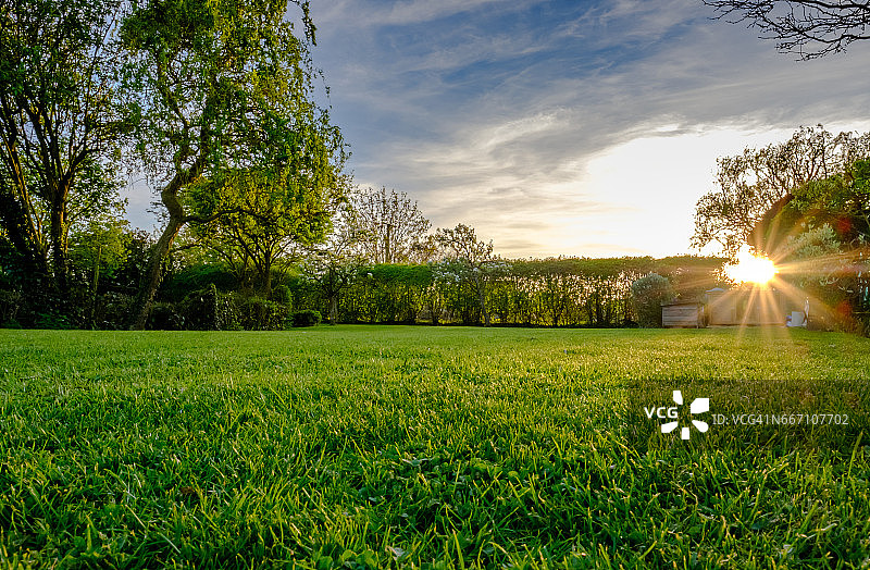 晚春壮丽的日落，显示了最近修剪和维护良好的大草坪在农村的位置。图片素材
