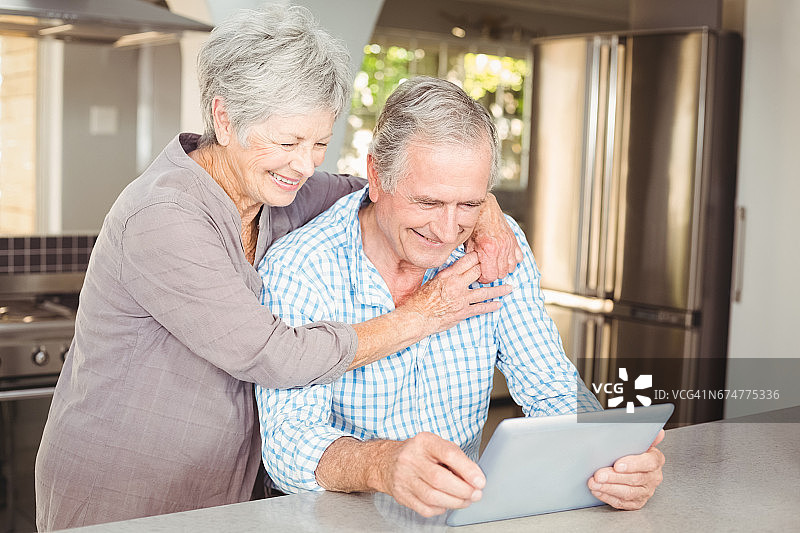 快乐的老女人拥抱用平板电脑的男人图片素材