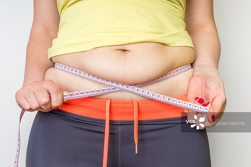 超重妇女用卷尺量肚子上的脂肪图片素材