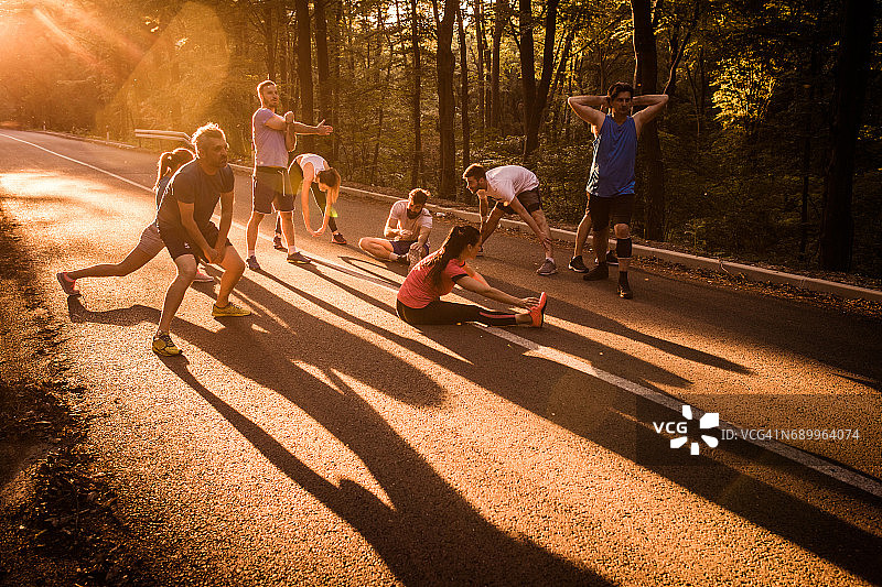 日落时分，马拉松赛前在公路上热身的一群跑步者。图片素材