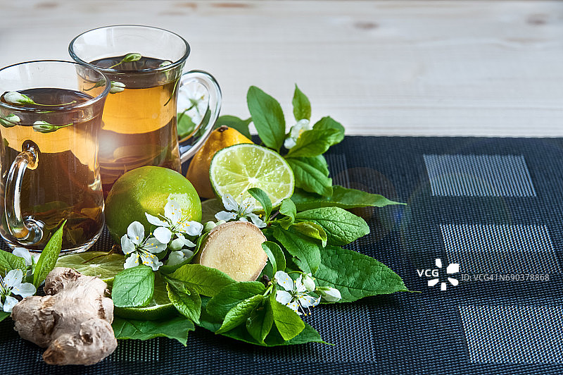 两个装着茶的透明杯子。绿茶，红茶，草药，茉莉花茶，柠檬和姜。茶的主题。烹饪、茶叶包装、食品生产、餐饮经营图片素材