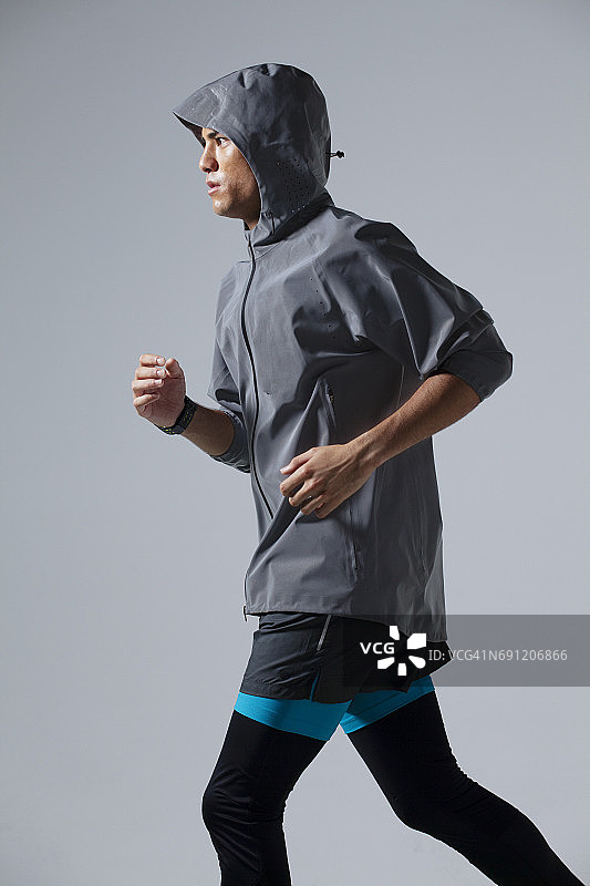 穿着运动服在灰色背景上跑步的男人图片素材