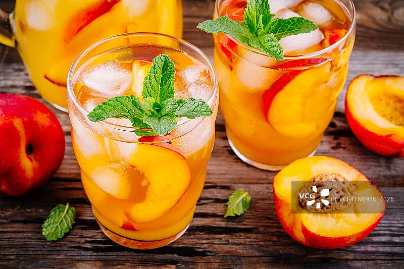夏季冷饮:自制的蜜桃桑格利亚汽酒加冰块和薄荷杯图片素材
