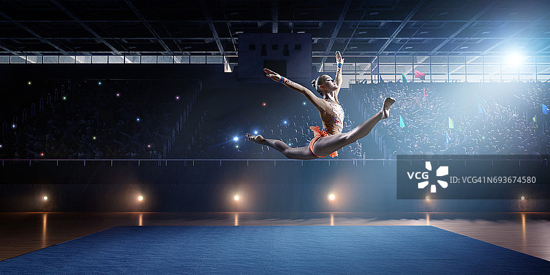 体操女运动员在大型专业舞台上跳跃图片素材