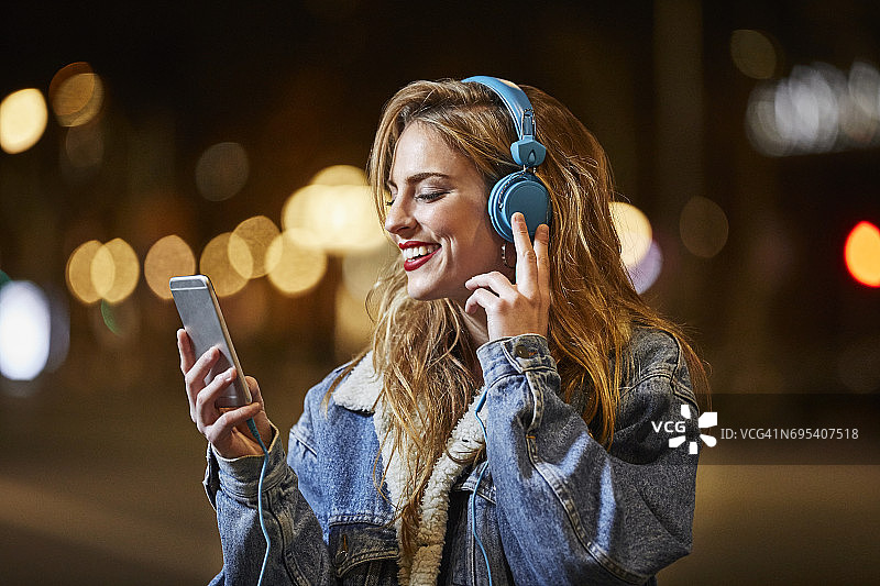 一个戴着耳机听音乐的快乐女人图片素材