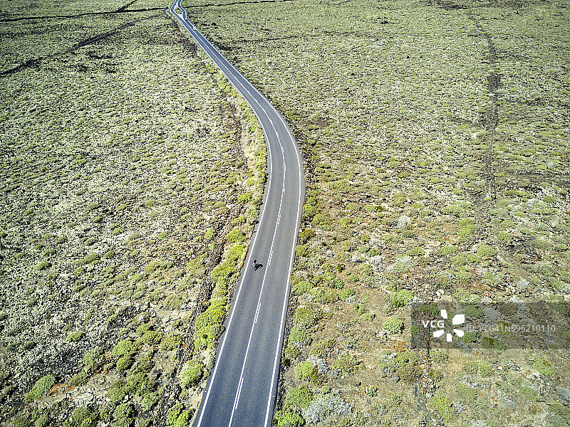 一个骑自行车的人在西班牙兰萨罗特公路上的航拍图像。图片素材