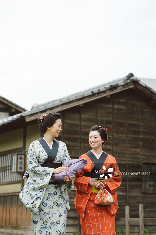 美丽的日本妇女穿着和服走在古老的村庄，江户时代图片素材