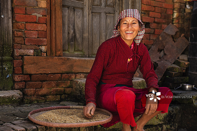 一名正在筛米的尼泊尔妇女，巴克塔普尔图片素材