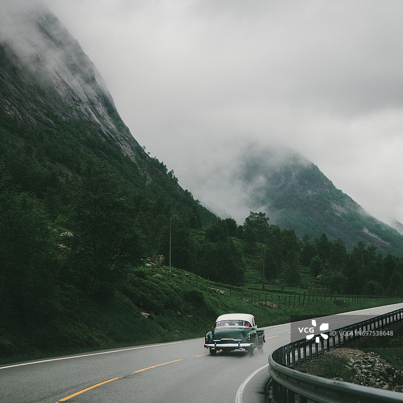 老式汽车行驶在挪威山区蜿蜒的道路上图片素材