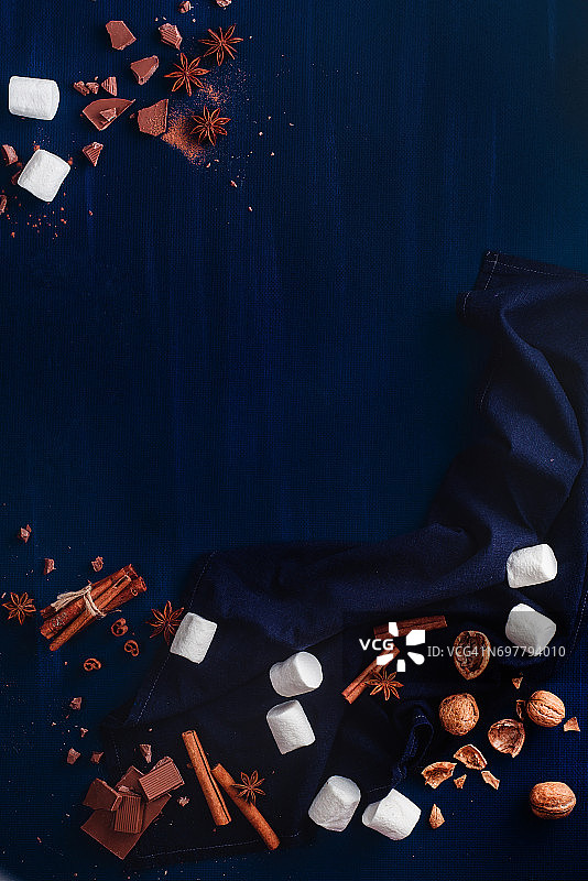 黑色复制空间框架与糖果:可可粉，棉花糖，核桃，巧克力和肉桂在黑色的背景图片素材
