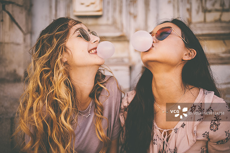 年轻女性在城市里用泡泡糖吹泡泡图片素材