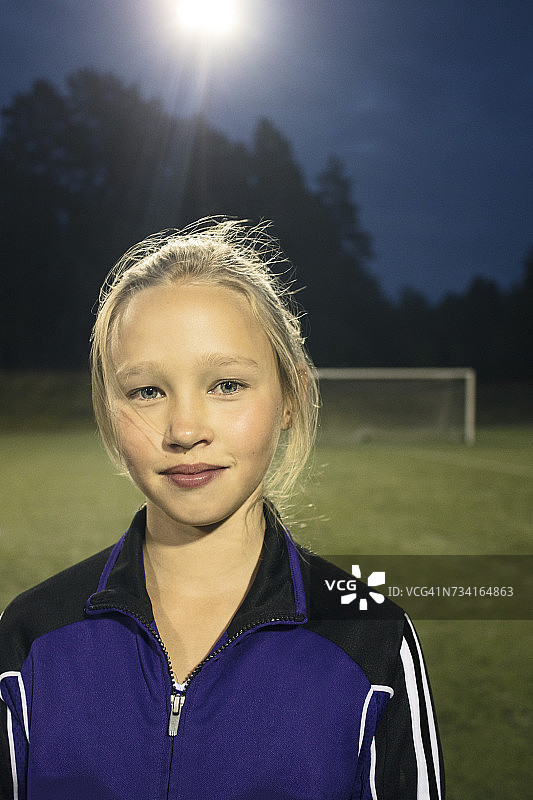 一个自信的女孩晚上站在足球场上图片素材