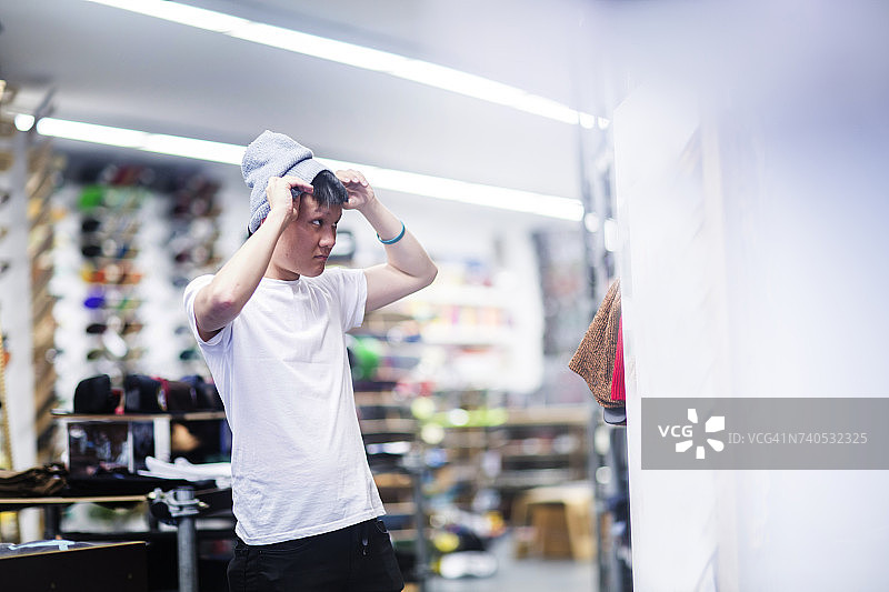 年轻男性滑板手在滑板店试穿针织帽图片素材