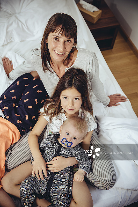 幸福的母亲和她的三个孩子在床上图片素材