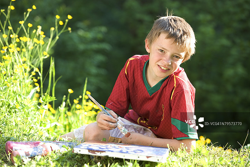 男孩(6-7)在草地上画画，肖像图片素材