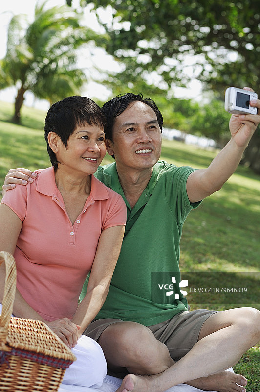一对成熟的夫妇在公园里野餐并拍下他们自己的照片图片素材