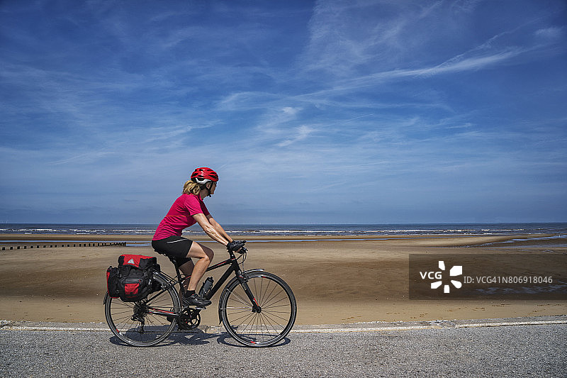女性骑自行车旅行沿着海滨自行车道图片素材