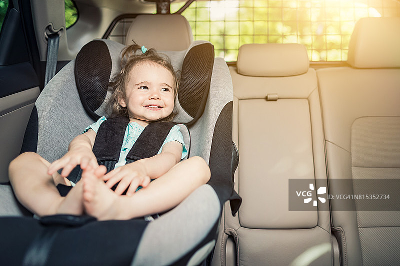 女婴扣在她的汽车座椅上。图片素材