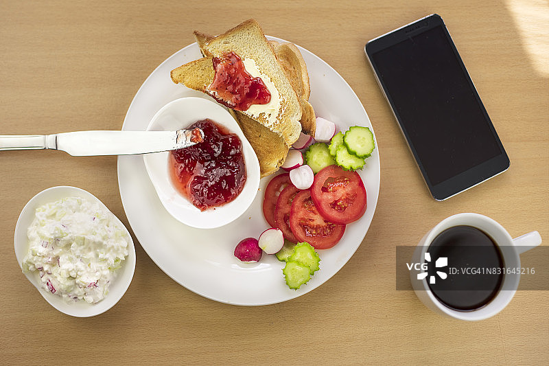 高角度的健康早餐和智能手机桌上。早晨的阳光图片素材