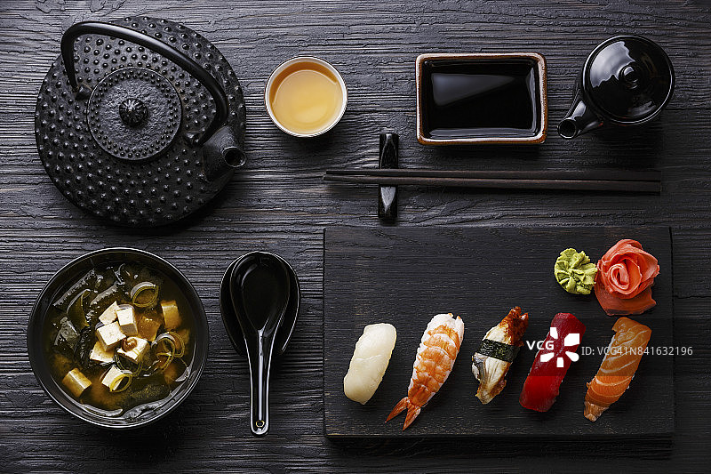 握寿司放在木制的上菜板上，味噌汤放在黑色的木制背景上图片素材