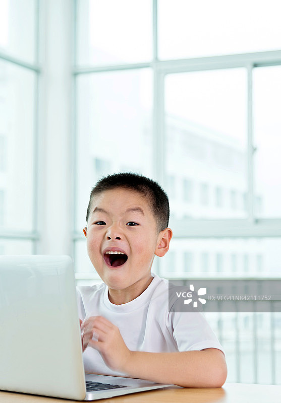 震惊亚洲男孩在互联网上用笔记本电脑图片素材
