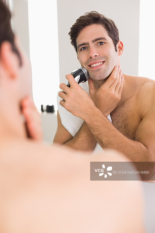 赤裸上身的男人用电动剃须刀刮胡子图片素材