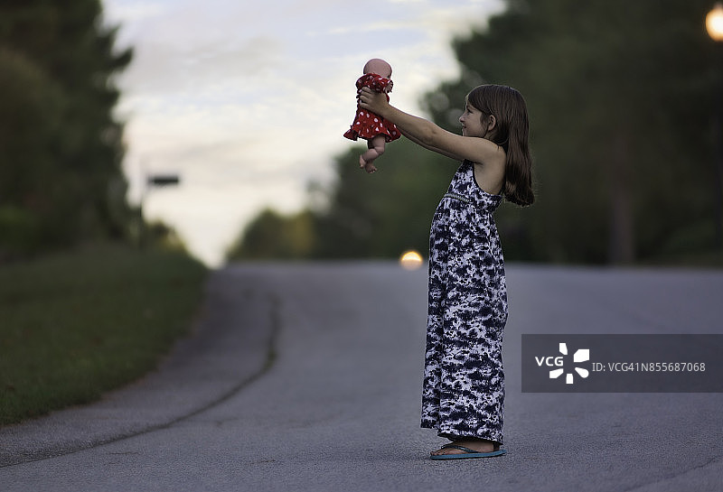 穿着拖地长裙的年轻女孩抱着一个洋娃娃图片素材