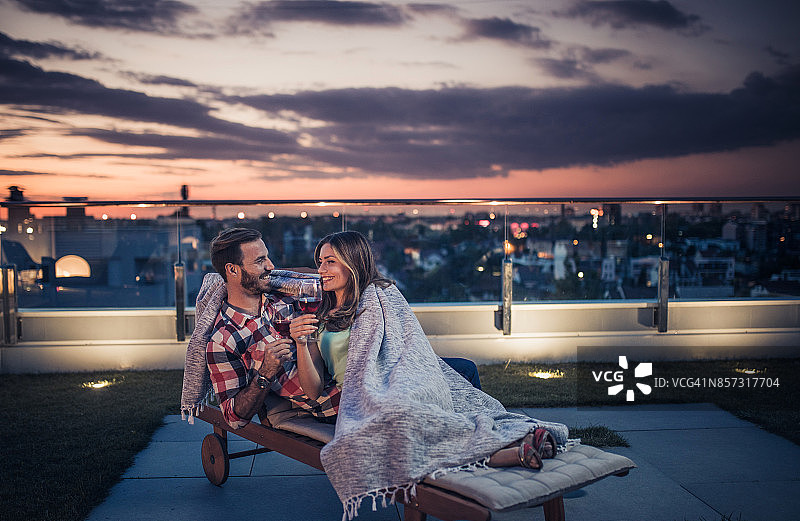 微笑的情侣在浪漫的夜晚享受在阳台上。图片素材