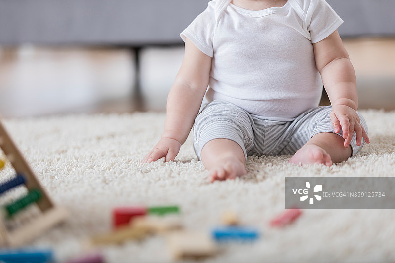 一个面目全非的女婴坐在家里的地毯上图片素材